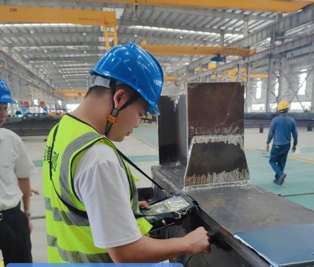 Inspector checking a fabricated component against the drawing in the workshop